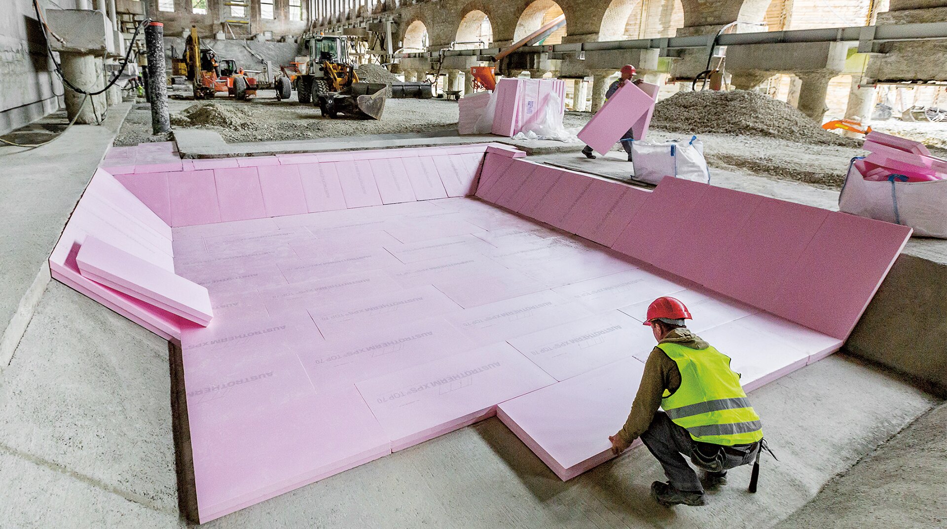 Museumsneubau unter historischer Halle in Ingolstadt. EIn Bauarbeiter Verlegt XPS_Platten von Austrotherm im historischen Gebäude. DIese wirkt wie ein riesiges Gewölbe.