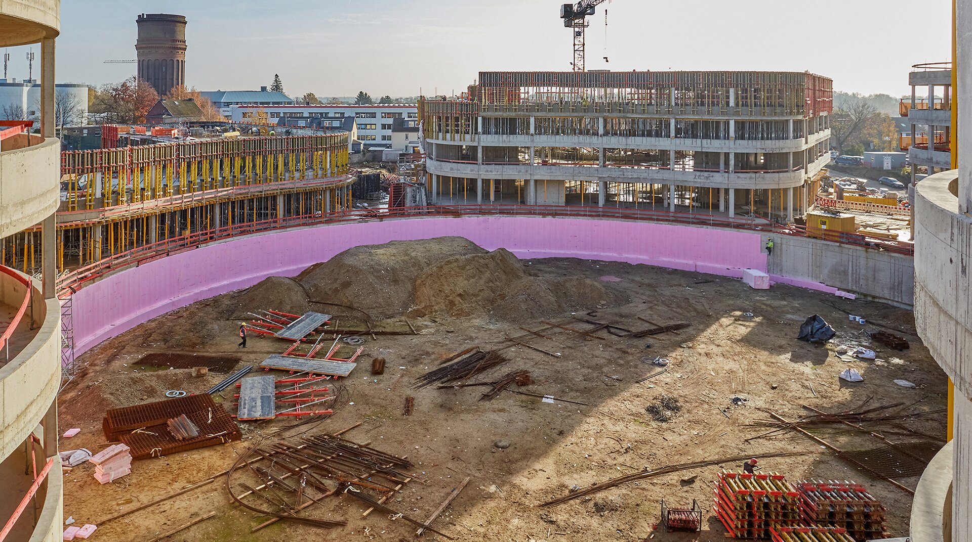 Man sieht den damals im Bau befindlichen SMS Campus in Mönchengladbach. Die inneren Wände werden mit den Platten von Austrotherm überdeckt, an den Rändern des Kreisförmigen Innenhofes sieht man die sich im Bau befindenden Bürogebäude.