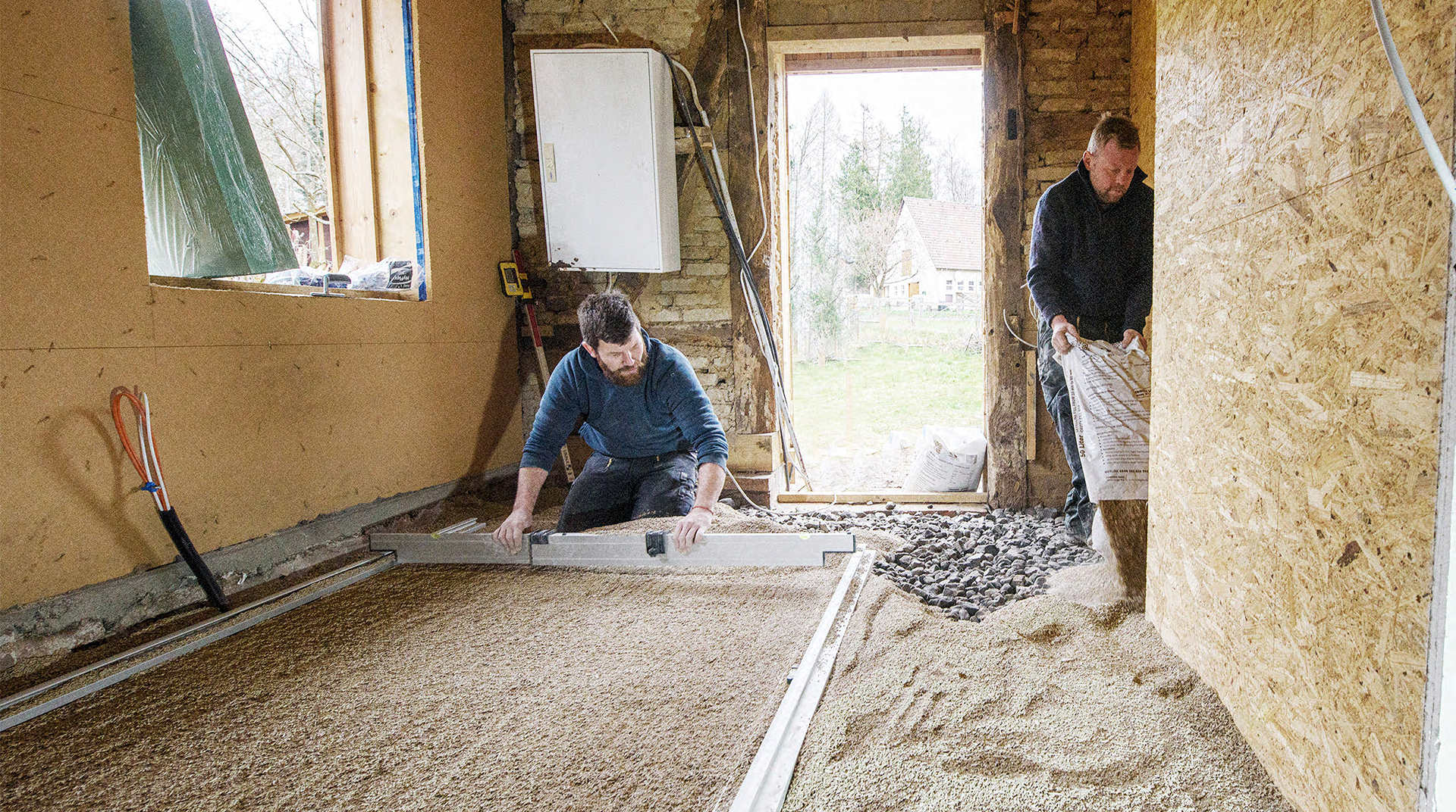 Handwerker beim schütten und glattziehen der Bodenunterfütterung.