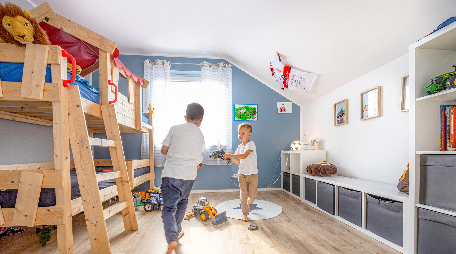 Großes, helles Kinderzimmer mit Etagenbett und zwei Jungs beim spielen