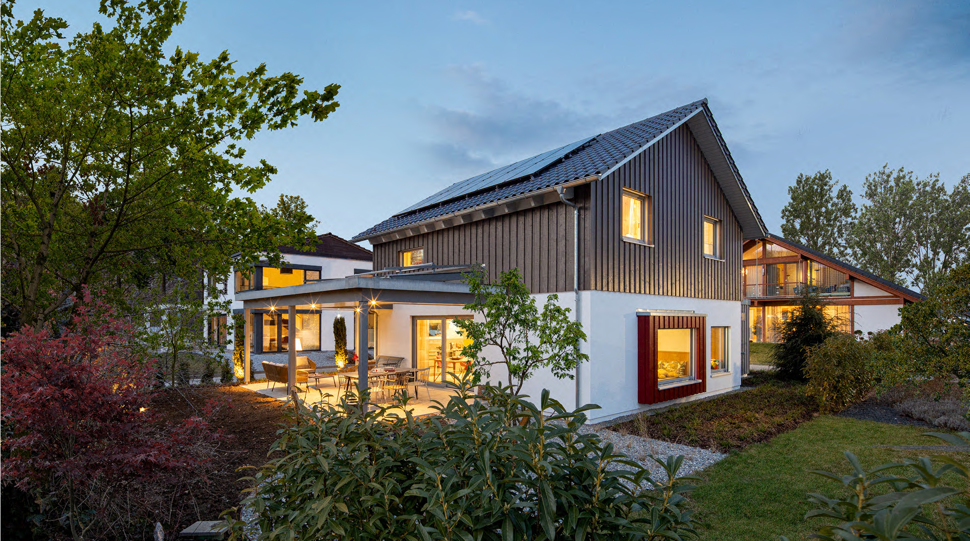 Ansicht von hinten mit Terrasse und Garten am Abend