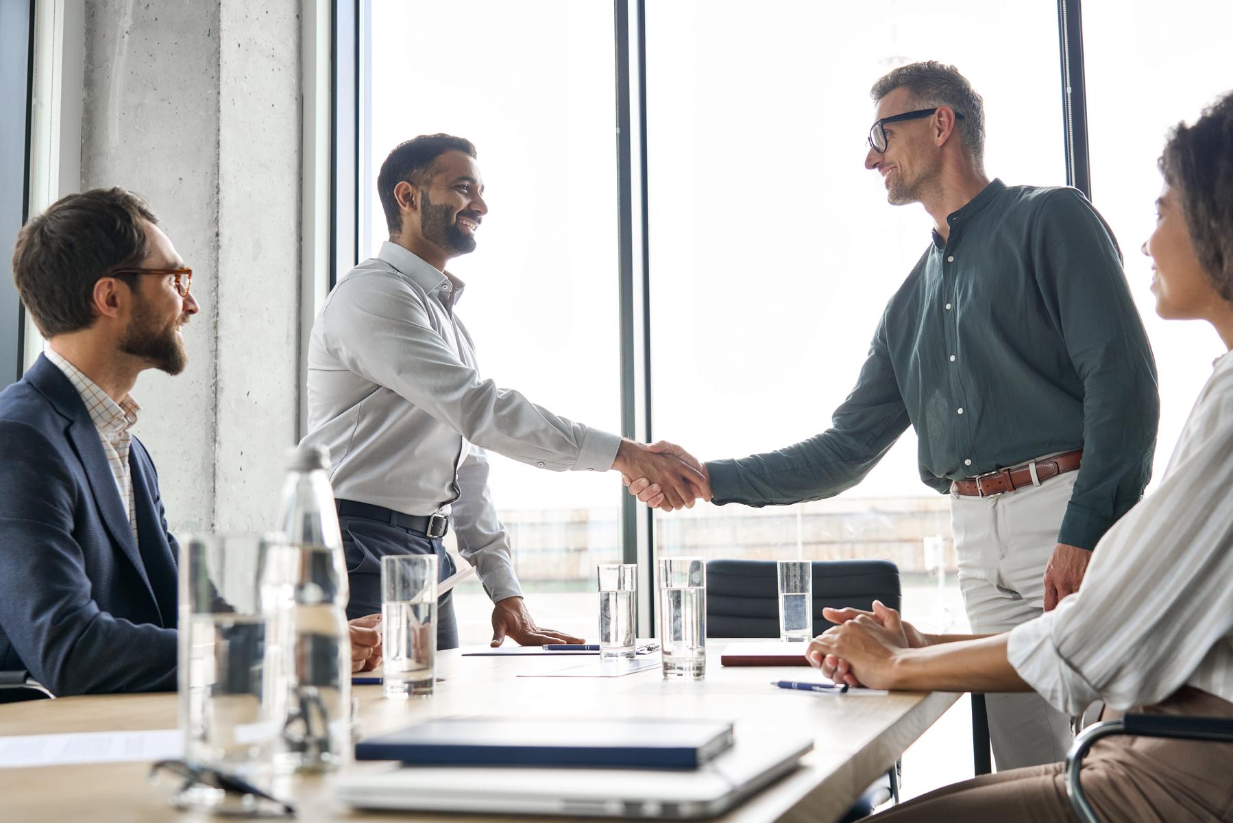 Investoren schütteln sich in einem Besprechungszimmer die Hände